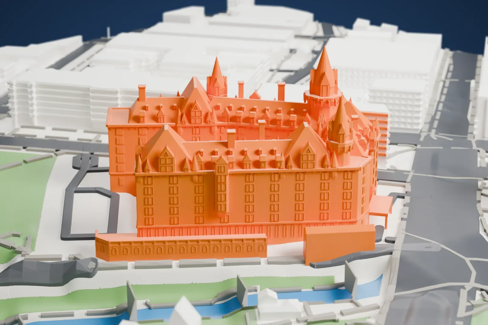 A white 3D print of the Château Laurier, with its turrets, dormers and steep roofs, beside a park and a strip of water with city buildings around it.