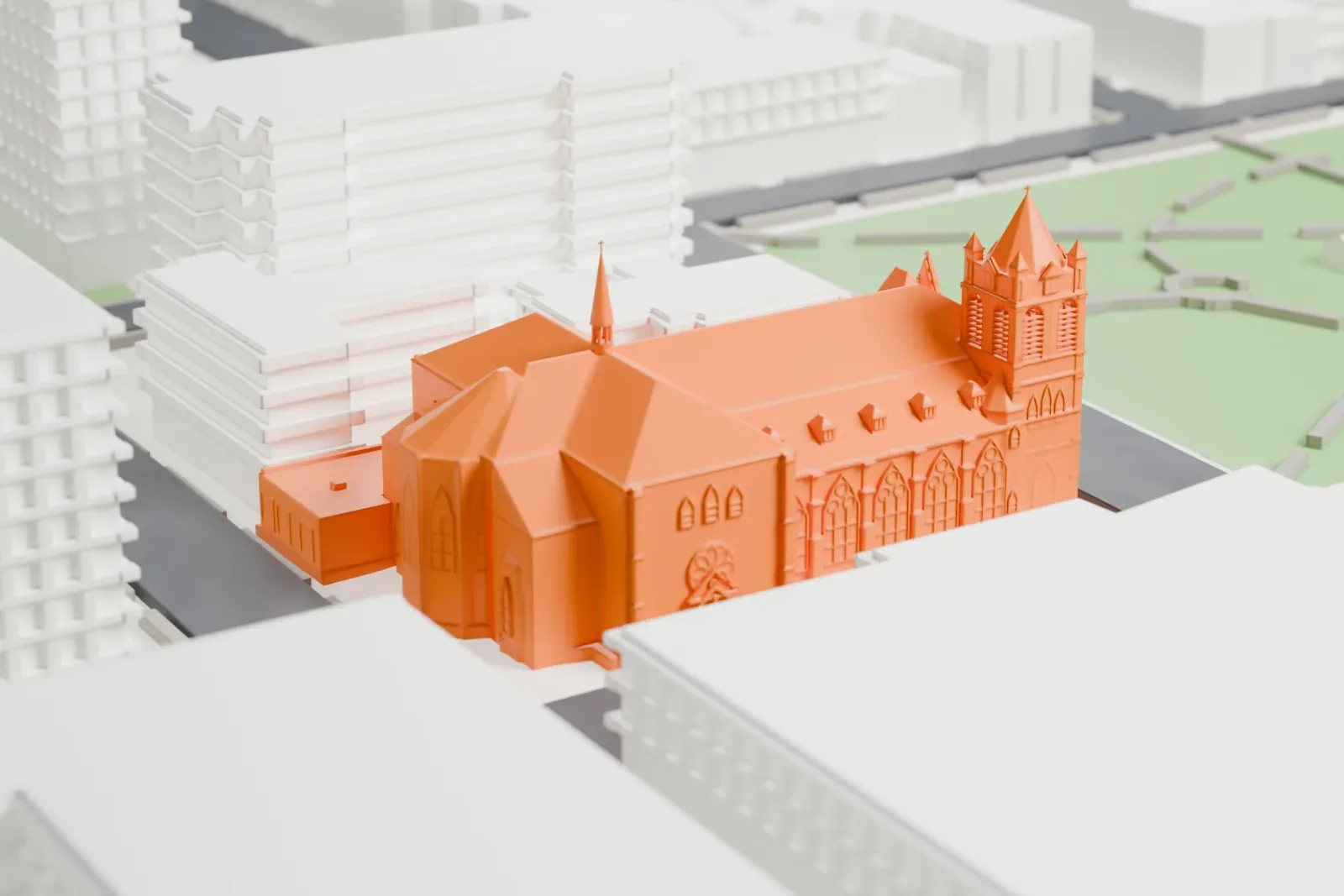 A white 3D print of the Church of Our Lady of Grace, a large church with a corner tower and a slim spire, on a city block beside a park.