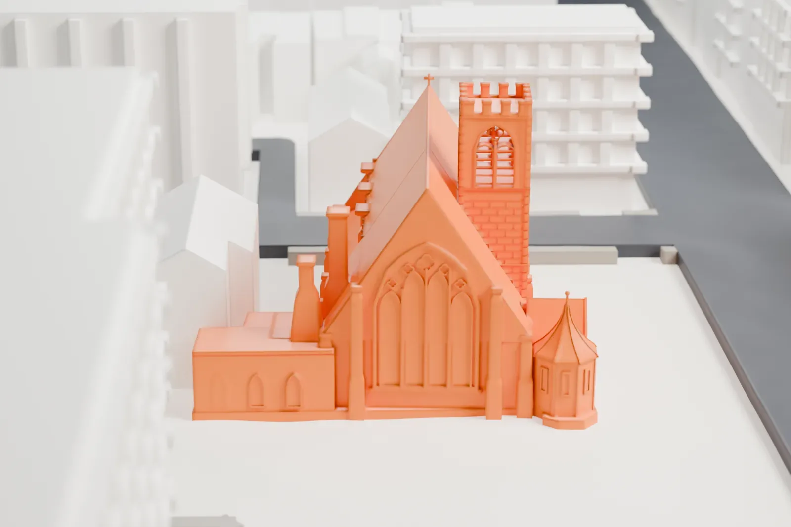 A white 3D print of the Church of the Holy Innocents, a church with a square battlemented tower and a large pointed window, among larger buildings and streets.