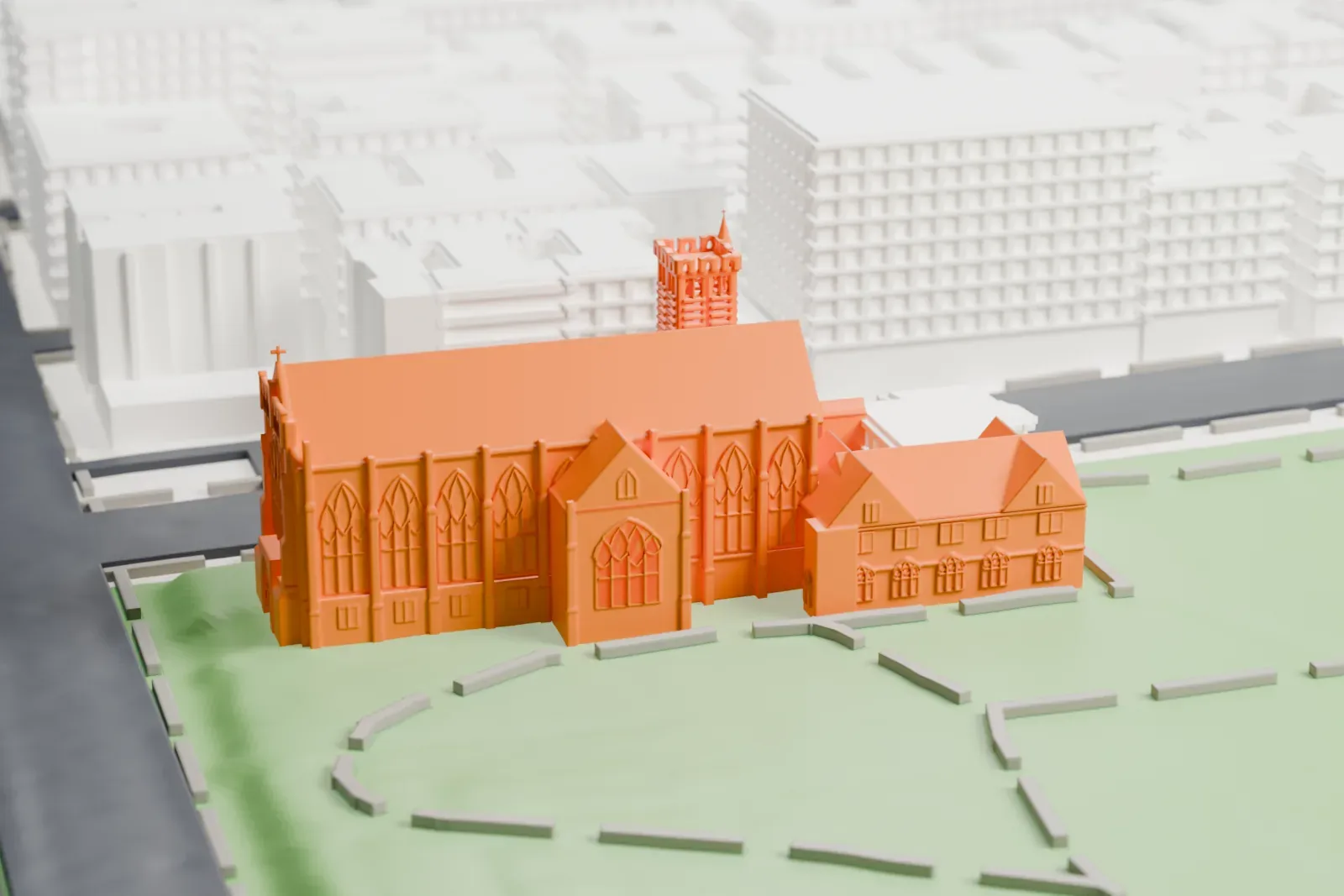 A white 3D print of the Church of the Intercession, a long Gothic church with a square tower and tall pointed windows, standing on green grounds with winding paths.