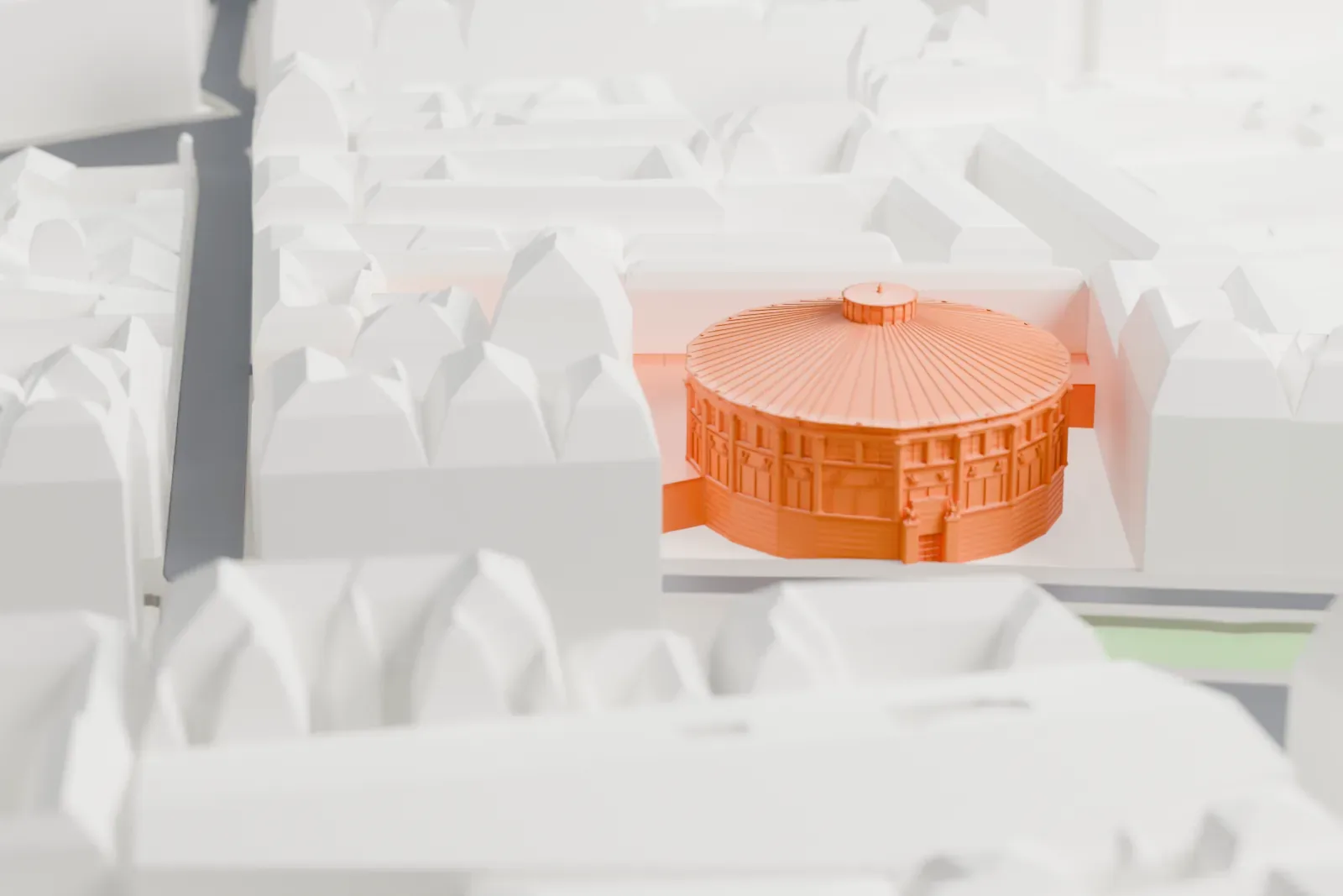 A white 3D print of the Cirque d'Hiver Bouglione, its oval form and shallow roof rising among the surrounding streets and buildings.