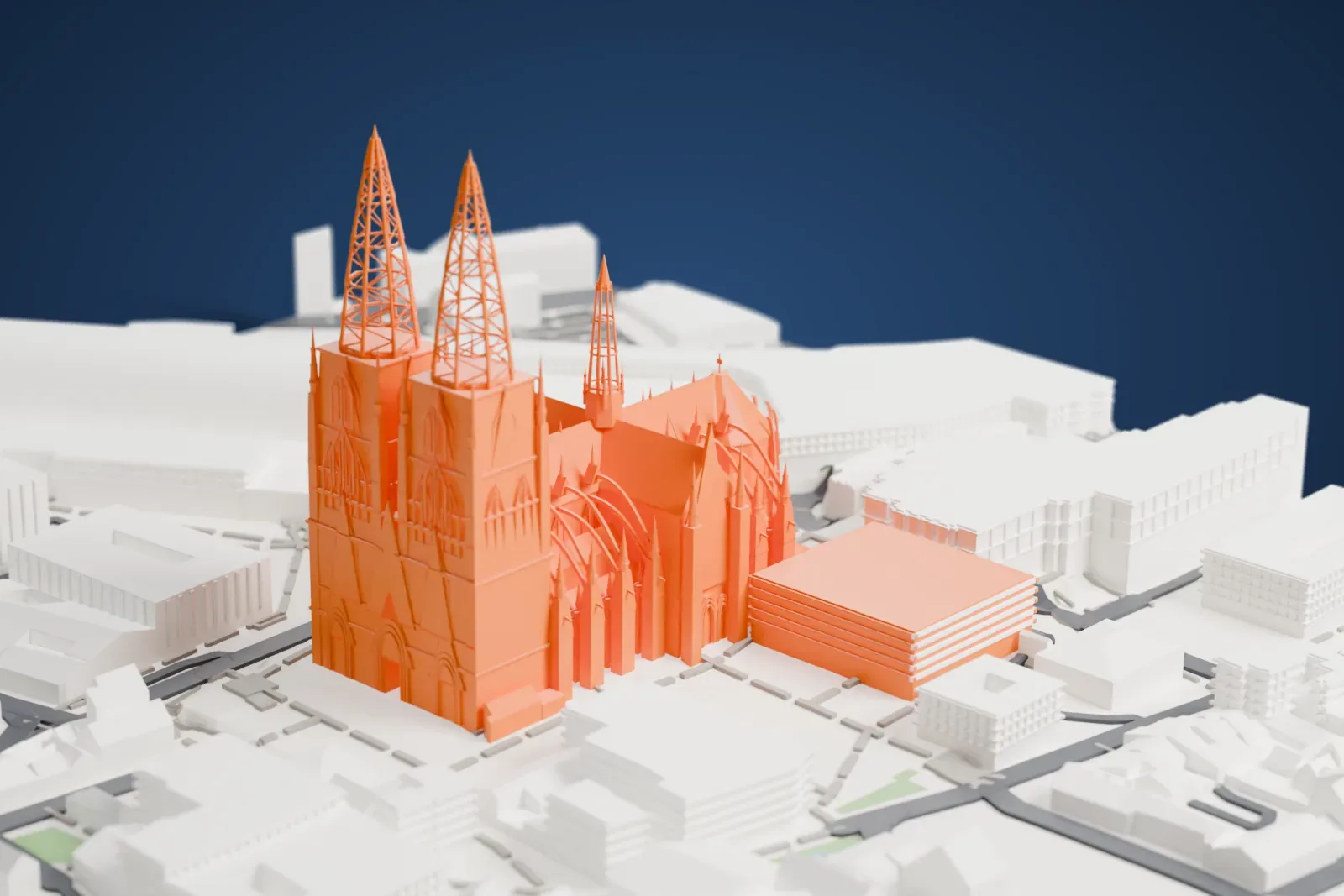A white 3D print of Cologne Cathedral, with its two lattice spires, tall nave and slender pinnacles, set among surrounding city buildings and a large curved roof.