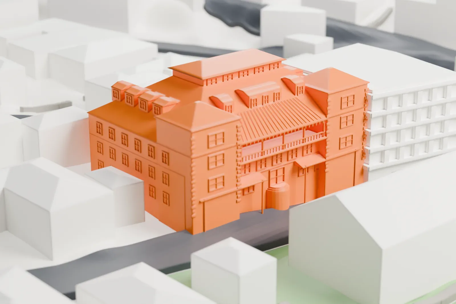 A white 3D print of the Copper Queen Hotel with dormers, small roof projections, and a recessed balcony among neighboring buildings and winding streets.