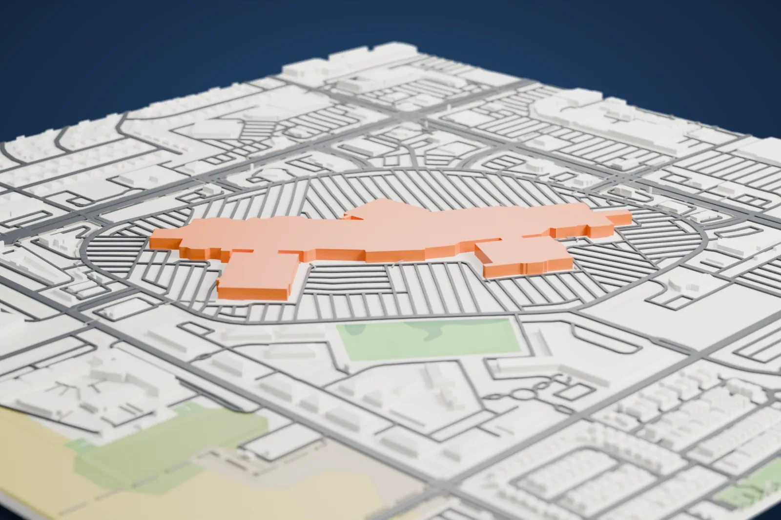 A white 3D print of Desert Sky Mall, a long, low, branching mall building inside an oval of parking lots, with streets and a green field nearby.