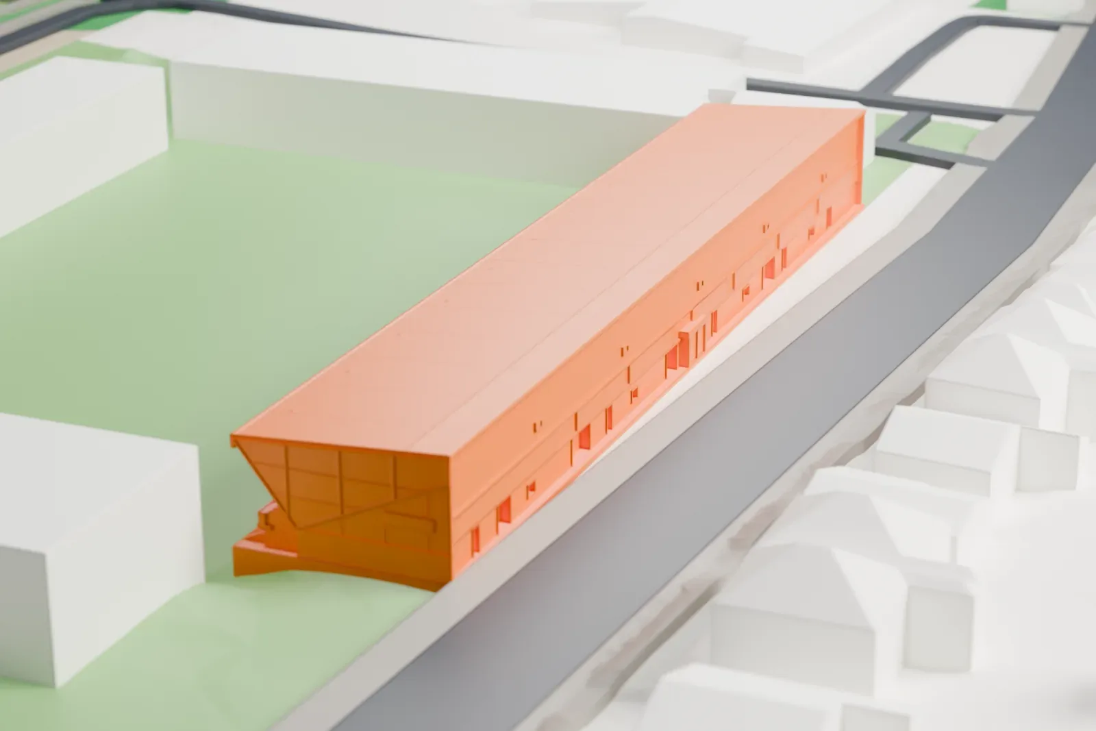 A white 3D print of the Main Stand at East End Park, a long shallow-roofed grandstand with a two-tier pitch face and tapering end screens, among the surrounding streets and buildings of Dunfermline.