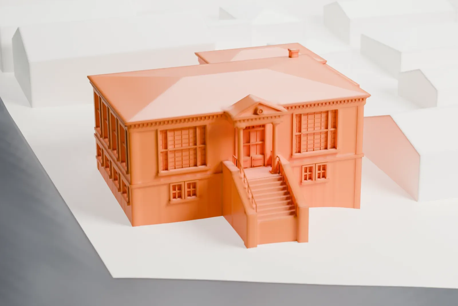 A white 3D print of the Edgewater Public Library, a building with a hipped roof and a stair up to its entrance, on a paved lot beside a street and nearby buildings.