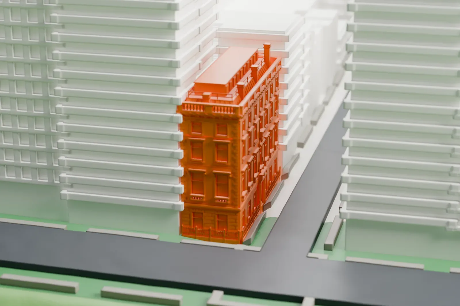 A white 3D print of the Edward S. Harkness House, a narrow mansion beside the edge of a park with a pond, among taller buildings.