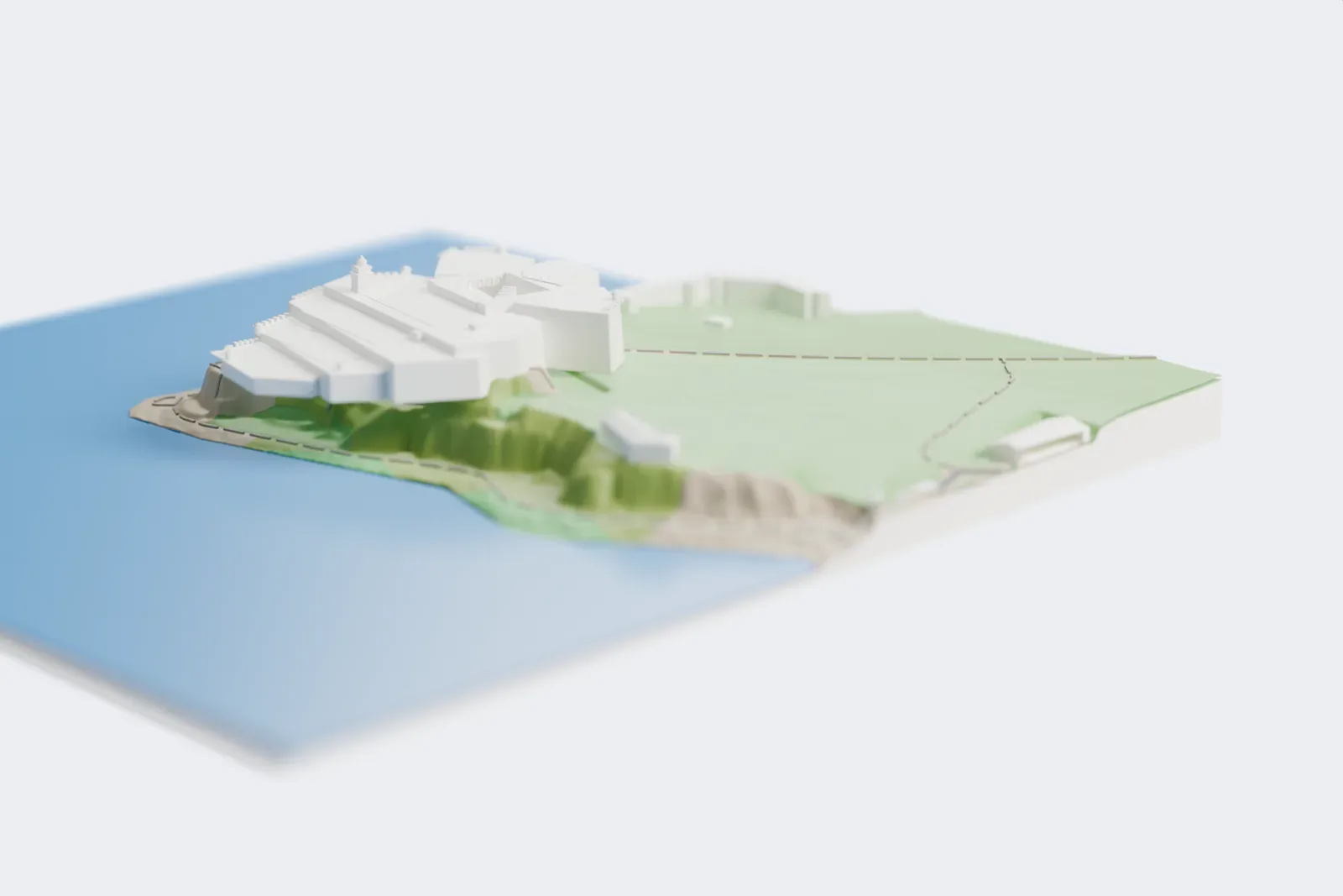 A white 3D print of El Morro, a terraced fortress with angular bastions and a small lighthouse tower, standing on a rocky headland above the sea with grassy ground behind it.