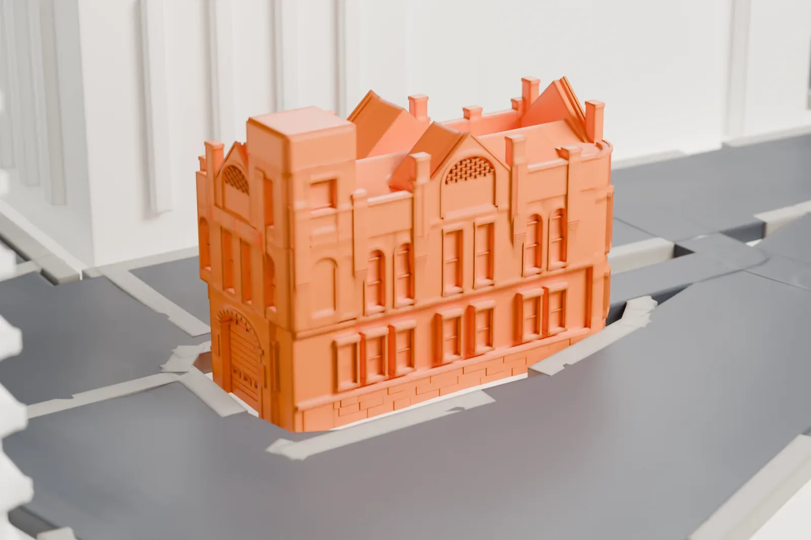 A white 3D print of a narrow firehouse with a gabled facade and a square tower, standing at a street corner.