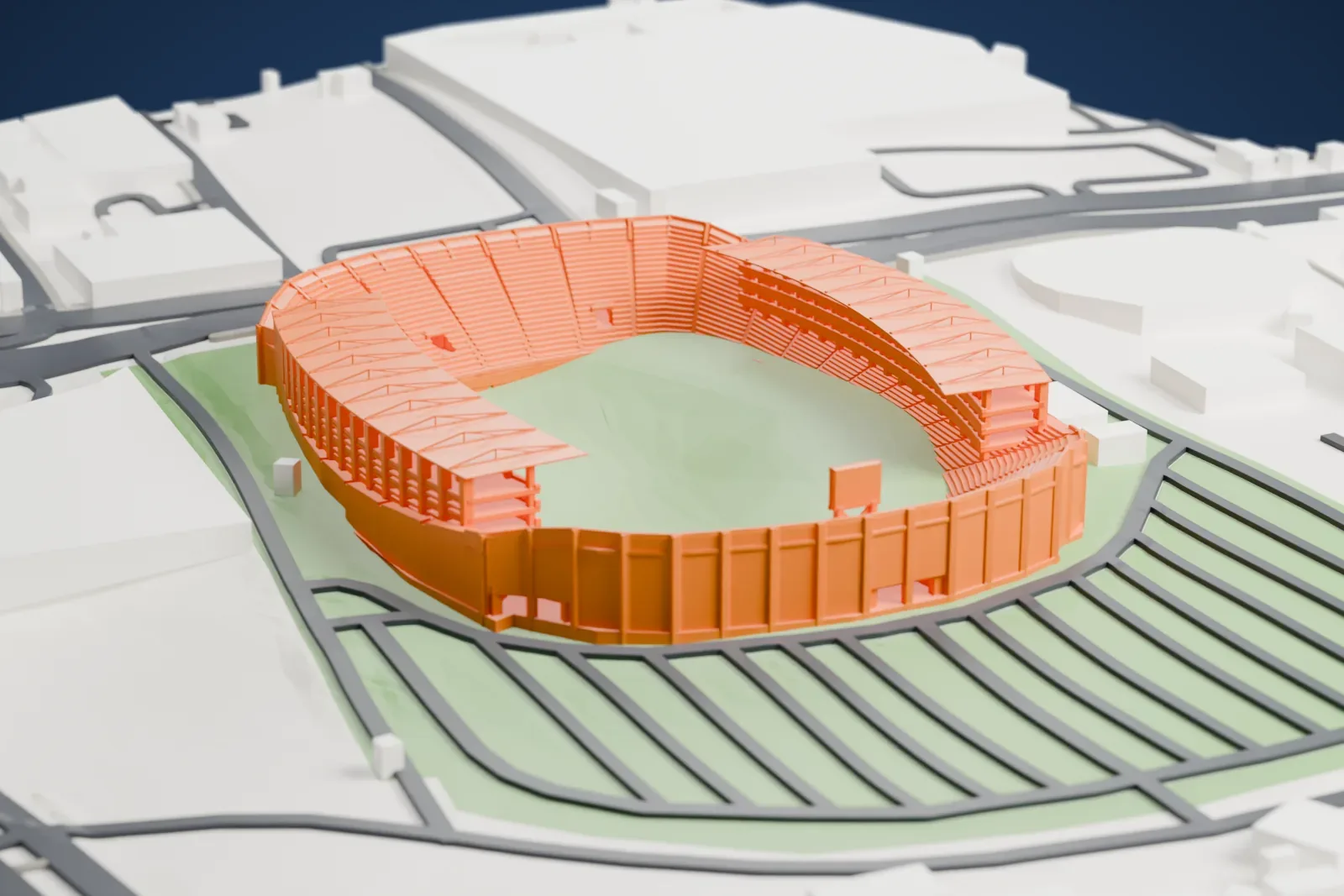 A white 3D print of the Estadio León, a compact open bowl with two separate sideline roofs, three balcony gallery levels and tall uncovered end terraces, among the surrounding streets and buildings of León.