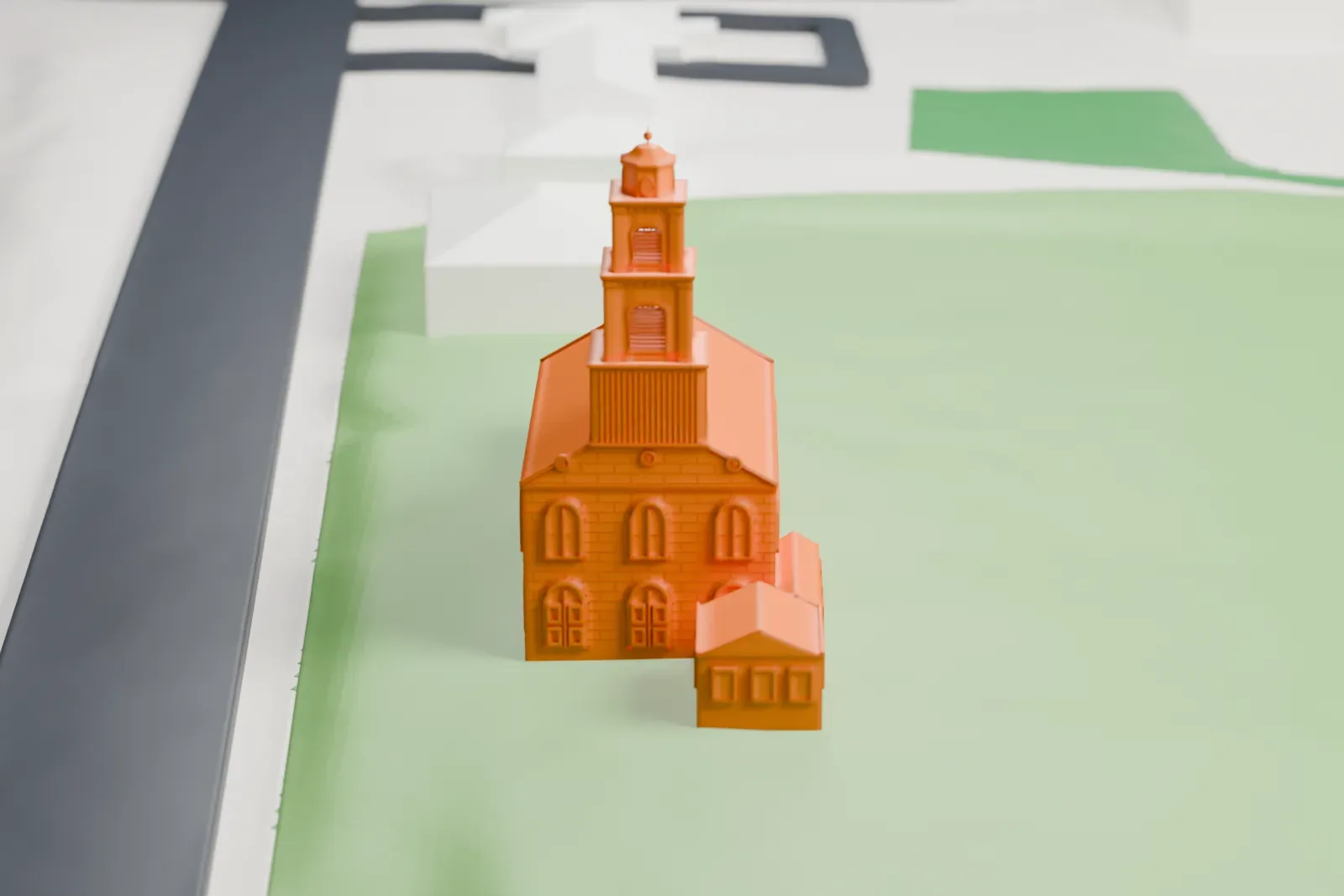 A white 3D print of Fairfield Dutch Reformed Church, a church with a stepped steeple and low side wings, standing on a lawn beside roads and a few buildings.