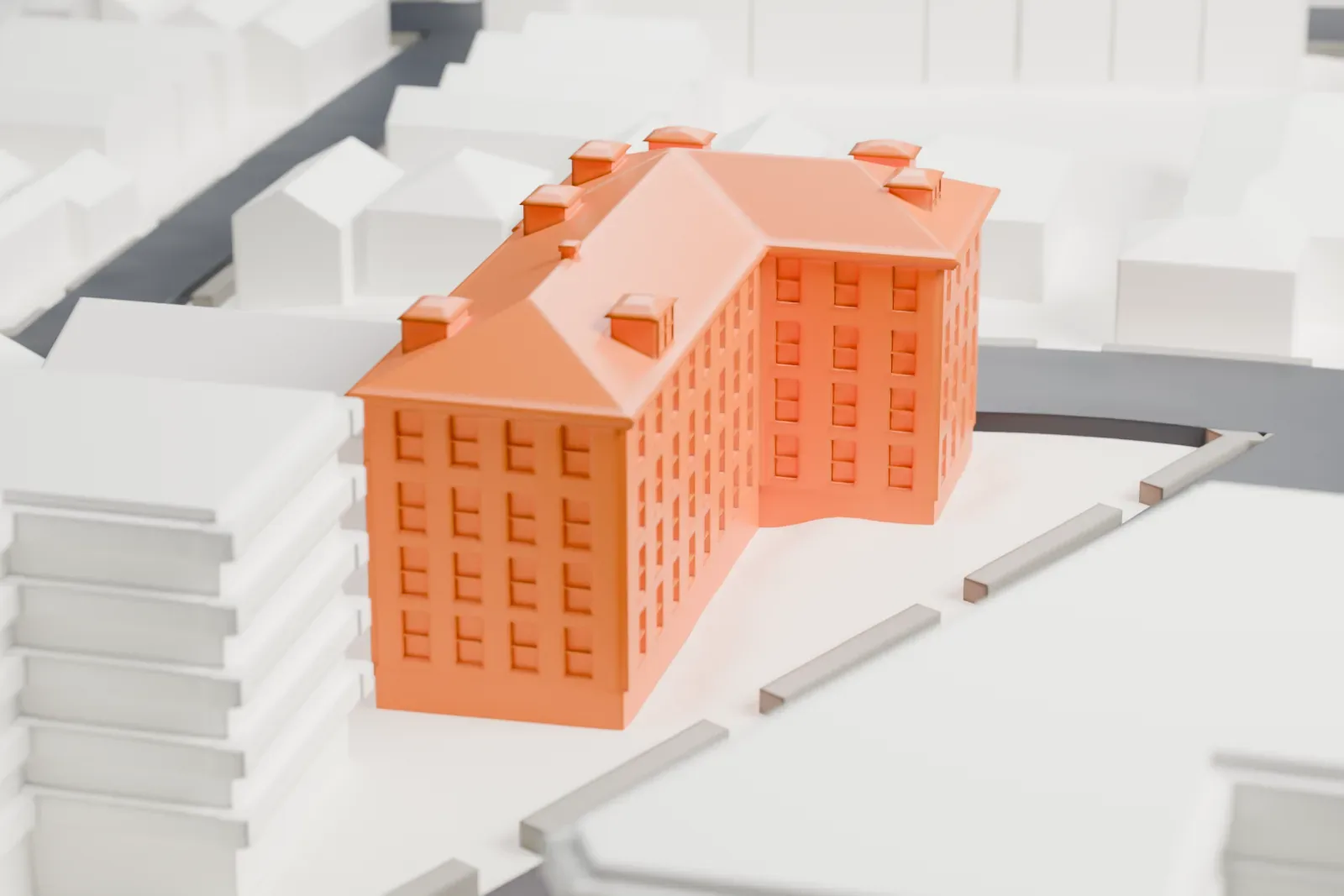 A white 3D print of the Fairmount Apartments, a tall L-shaped building with a hipped roof and small dormers, on a street corner among nearby buildings.