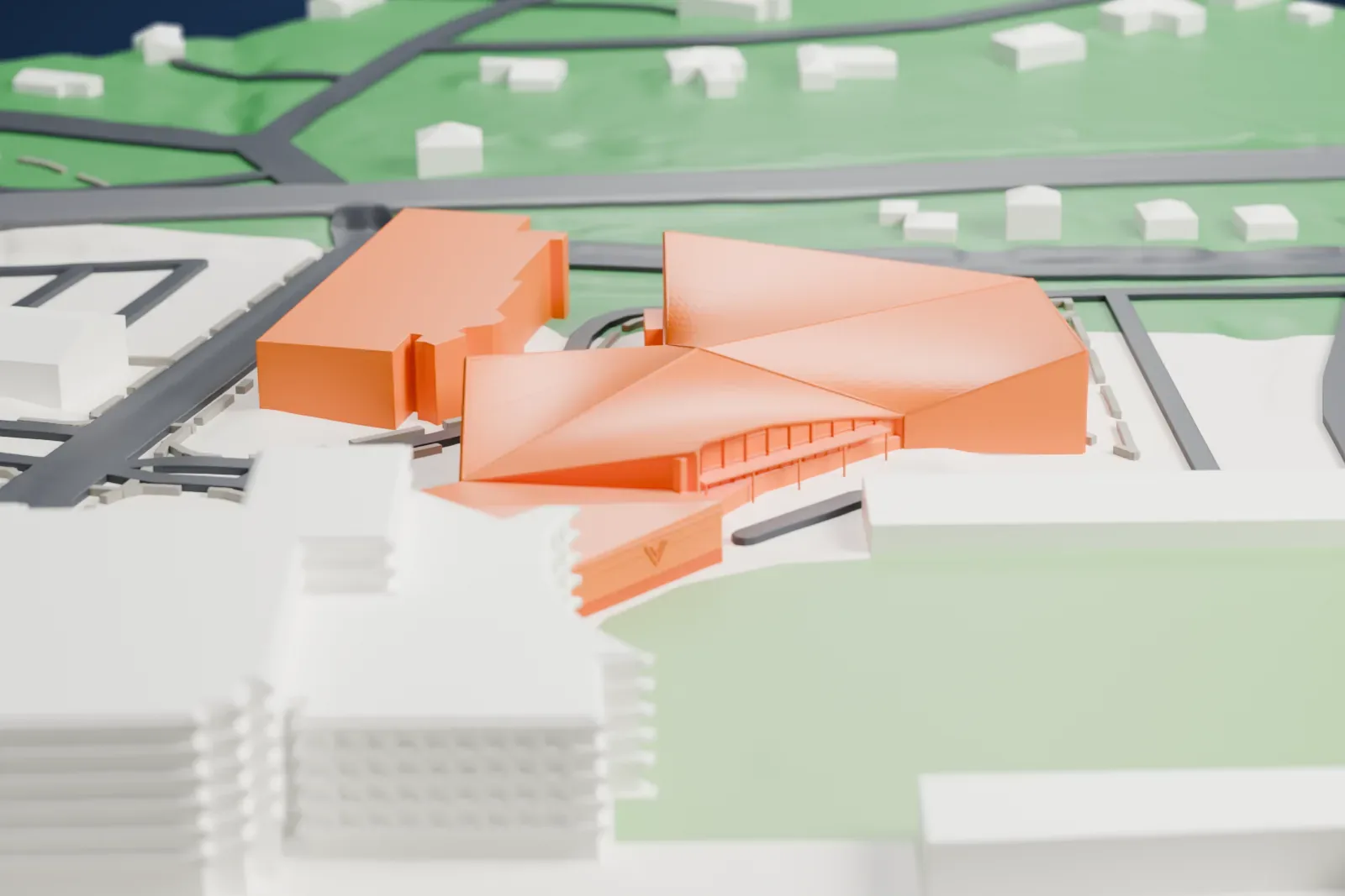 A white 3D print of the Finneran Pavilion, a low arena with a folded, peaked roof, beside a green playing field, parking areas and larger buildings.