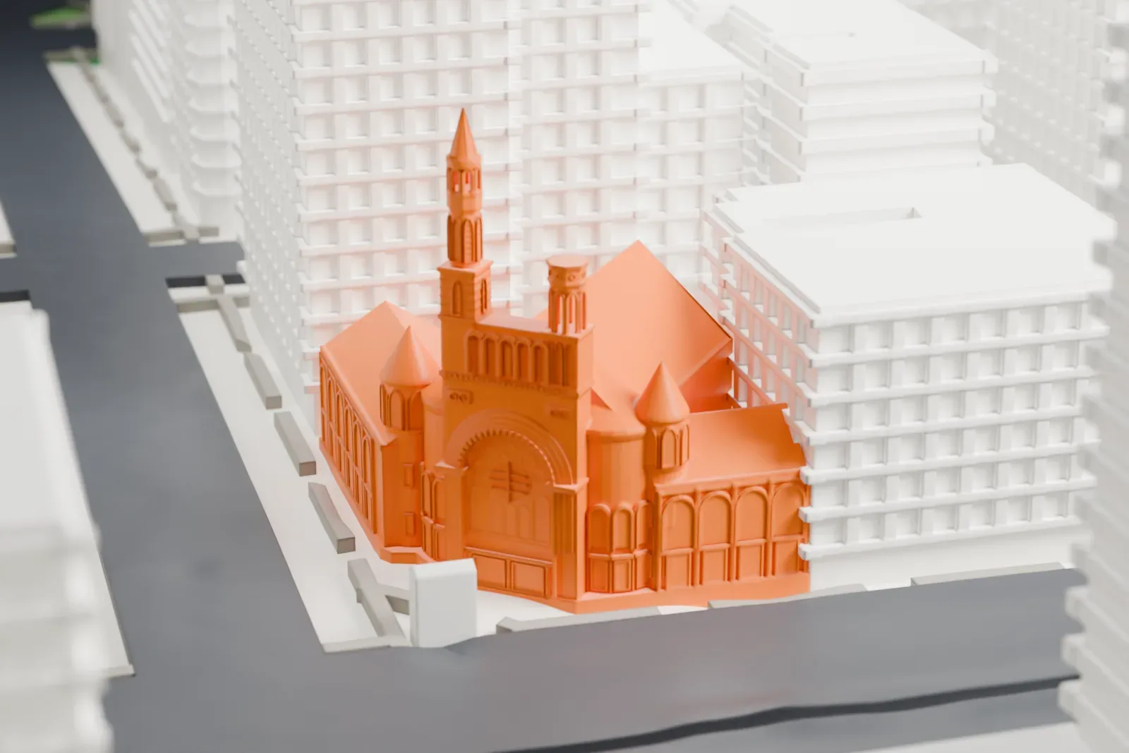A white 3D print of the First Baptist Church in the City of New York, with a tall spire and round turrets, surrounded by taller buildings.