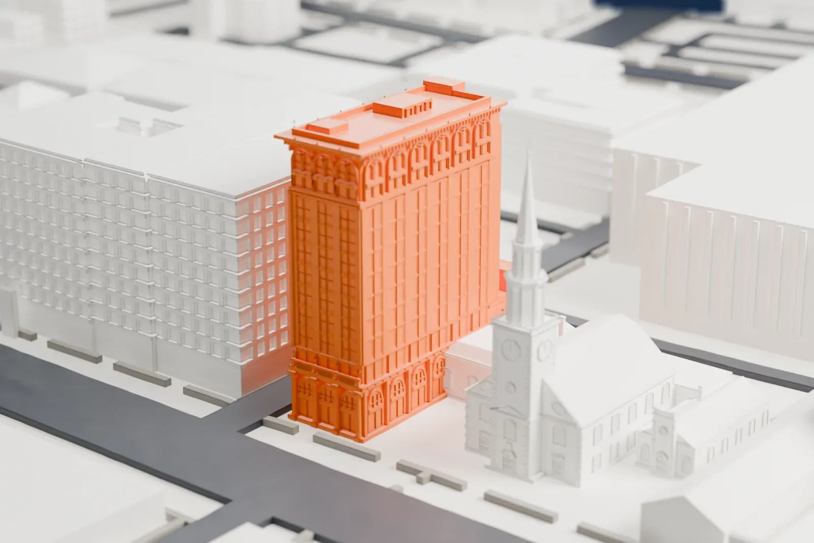 A white 3D print of the First National State Bank Building, a tall narrow building with arched windows near its top, beside a church with a tall spire and mid-rise buildings.