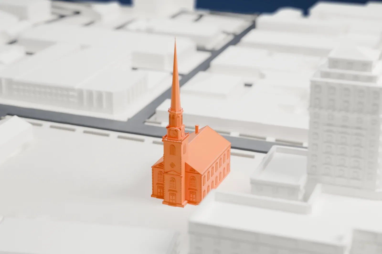 A white 3D print of the First Presbyterian Church of Elizabeth, a church with a tall slender steeple, beside a domed building and low city blocks.