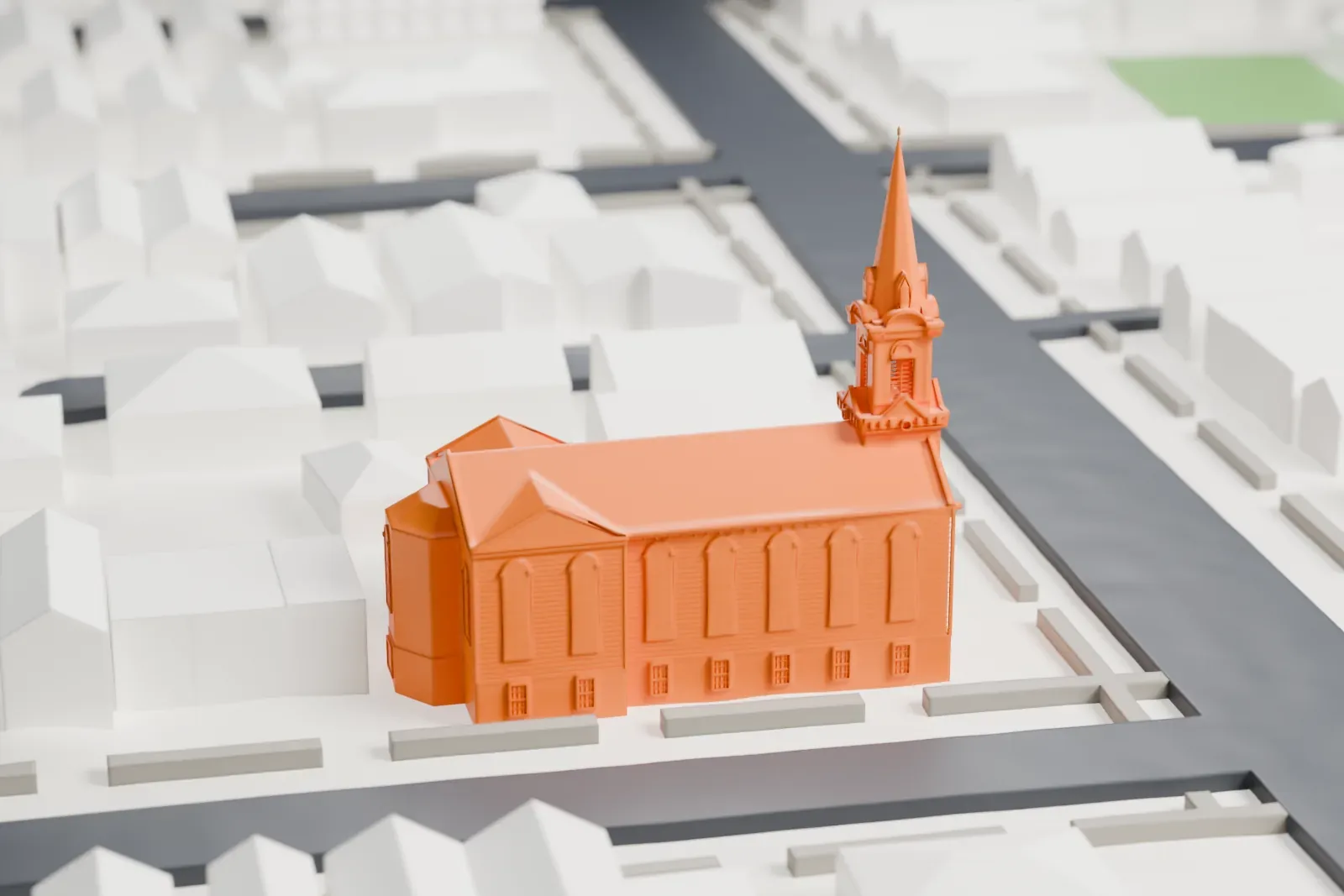 A white 3D print of a church with a tall spire standing at a street corner within a grid of low buildings and streets.