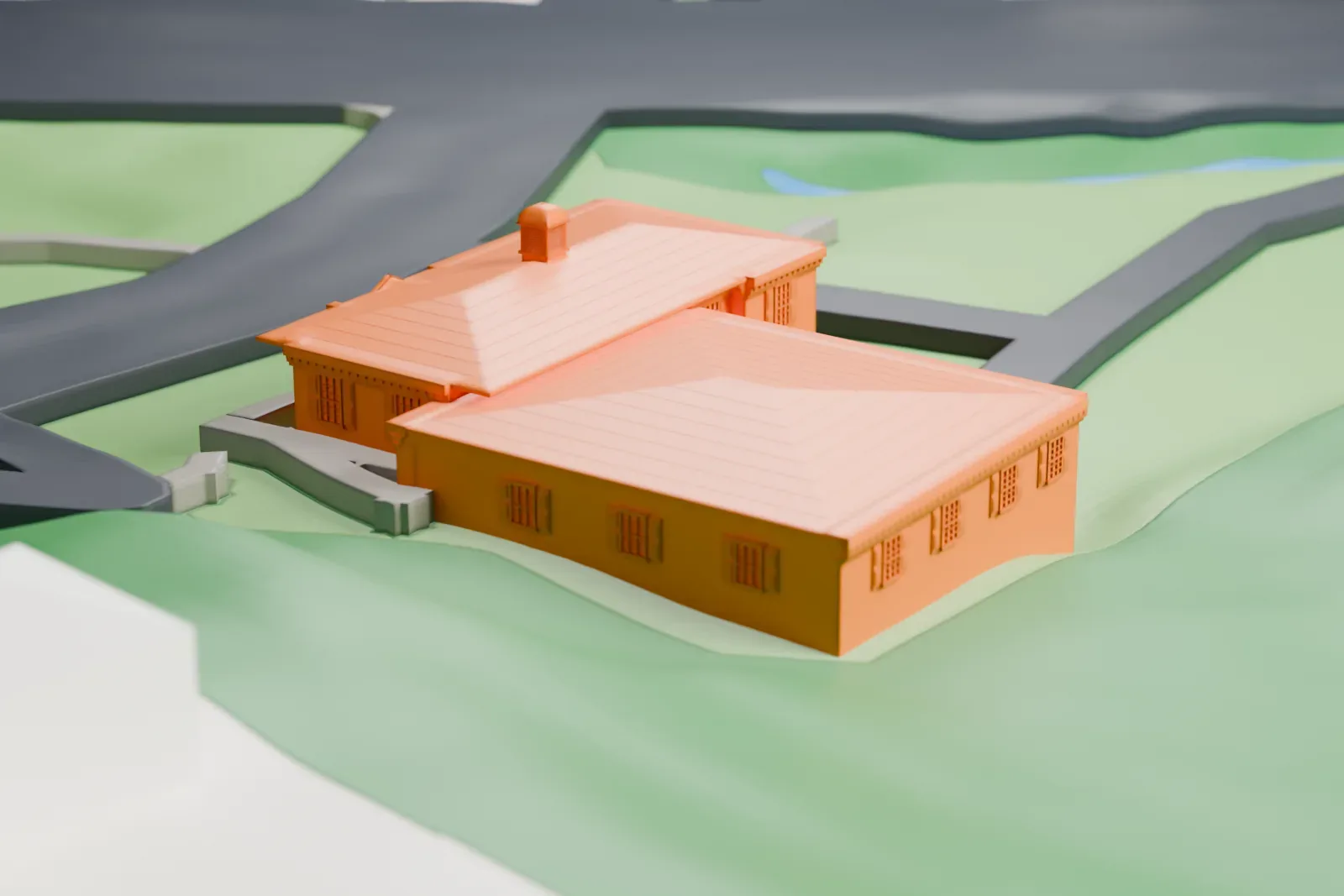 A white 3D print of a low village hall with hipped roofs and a chimney, on a small lot with lawns and winding roads.