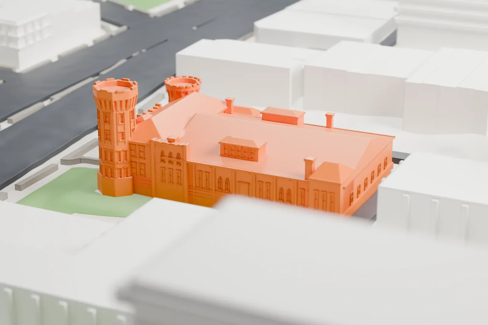 A white 3D print of the Flushing Armory, a castle-like building with a long roof and two towers, set on a grassy corner among streets and taller buildings.