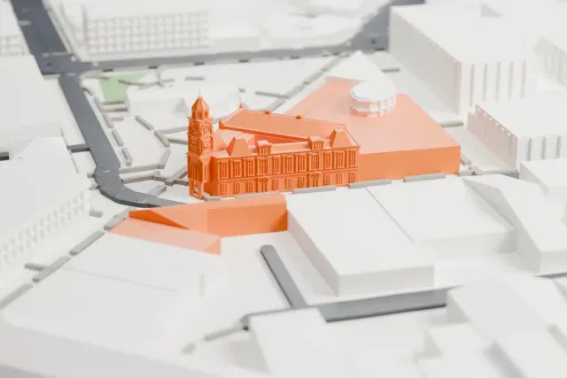 A white 3D print of Fremantle Town Hall, a two-story corner building with ornate windows and a hipped roof with small gables, among larger blocks and streets.