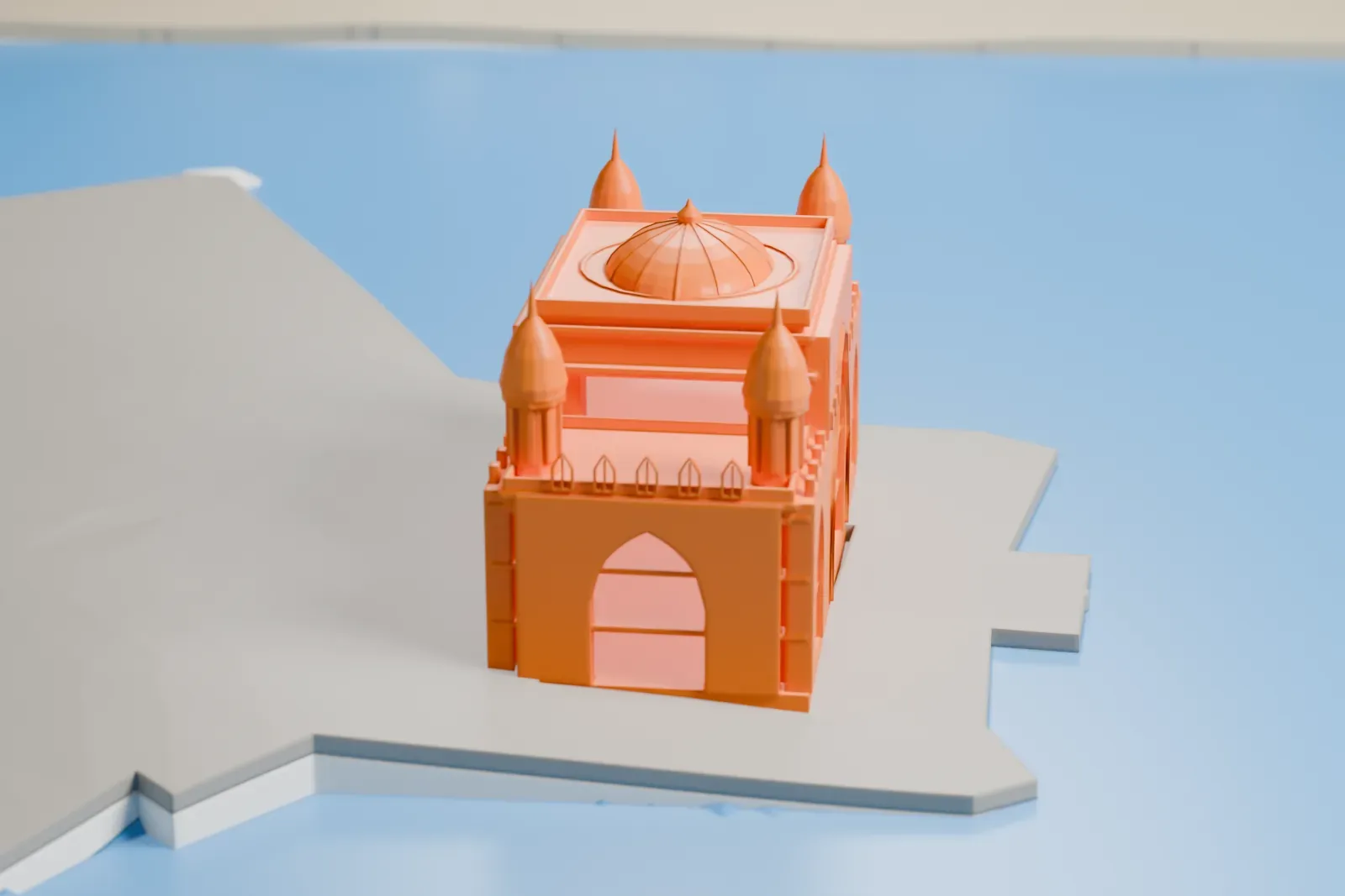 A white 3D print of the Gateway of India, a rectangular stone arch with a central dome and four pointed turrets, standing on a waterfront platform with open water around it.
