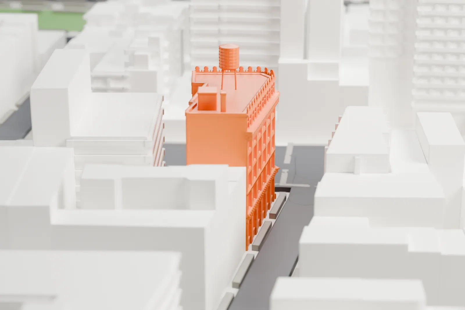 A white 3D print of the Germania Bank Building, a corner building with an ornate roofline, among low and mid-rise blocks with streets and green spaces around it.