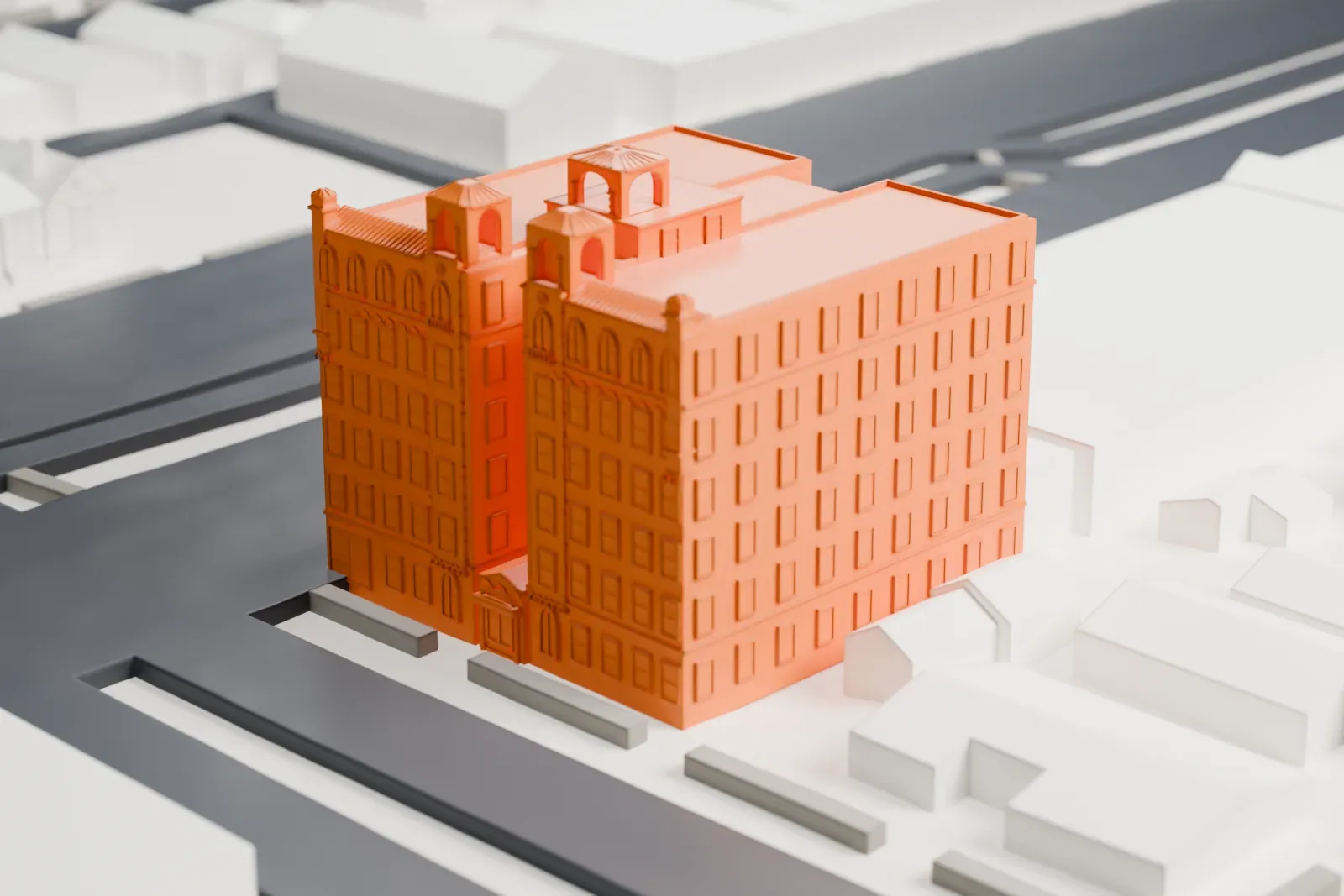A white 3D print of Granada Towers, a large block with several small turrets on its roof, standing among low buildings and streets.