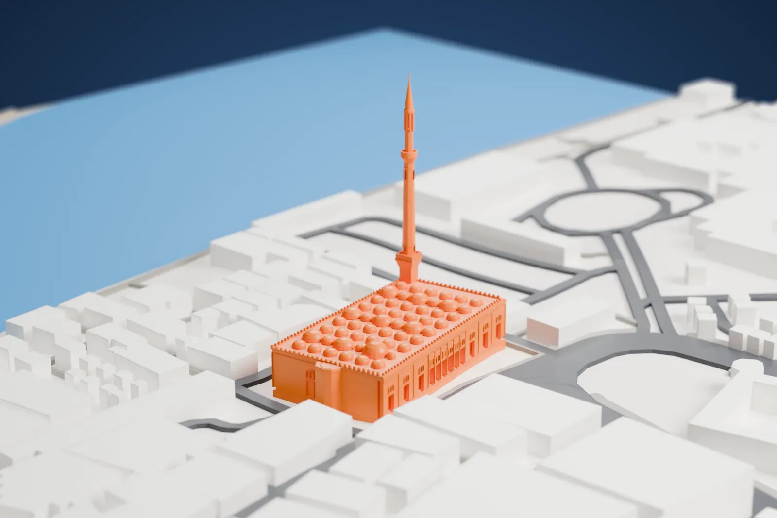 A white 3D print of the Grand Mosque of Dubai, with its minaret and domes rising among the surrounding streets and buildings.