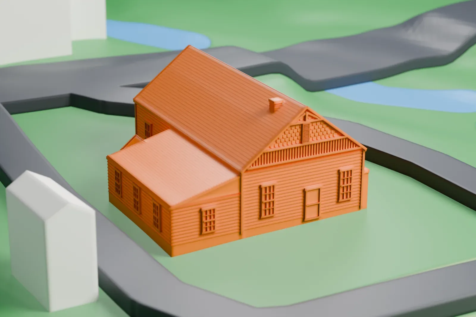 A white 3D print of Grange Hall in Wilton, a gabled wooden hall with a small side wing, on a green lawn ringed by a road with a stream nearby.