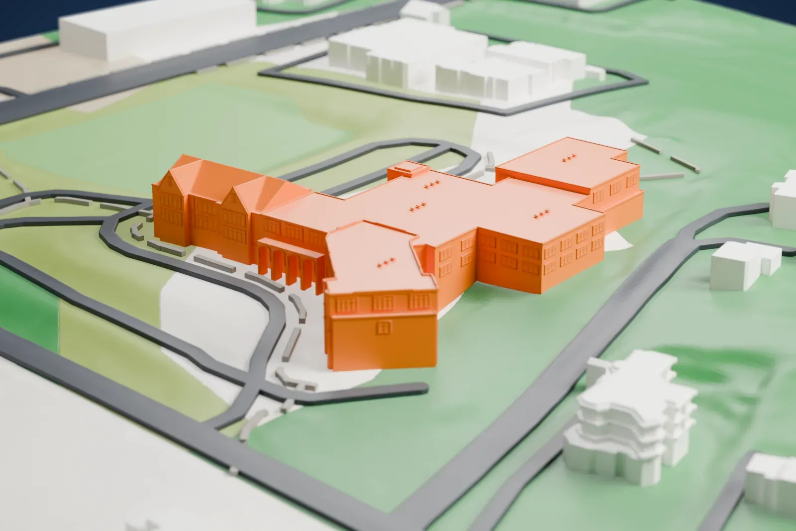 A white 3D print of Greens Farms School, a long low building with several wings, set among lawns, parking loops and a few small buildings.