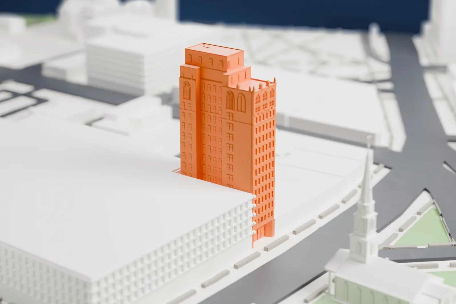 A white 3D print of the Griffith Building, a tall narrow high-rise with a stepped top, beside a green park with a church spire and nearby roads.
