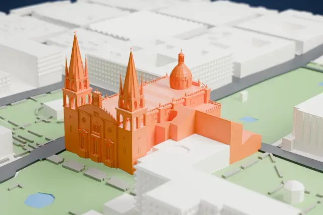 A white 3D print of the Guadalajara Cathedral, a long church with a ribbed dome and two tall spired towers, surrounded by green squares and streets.