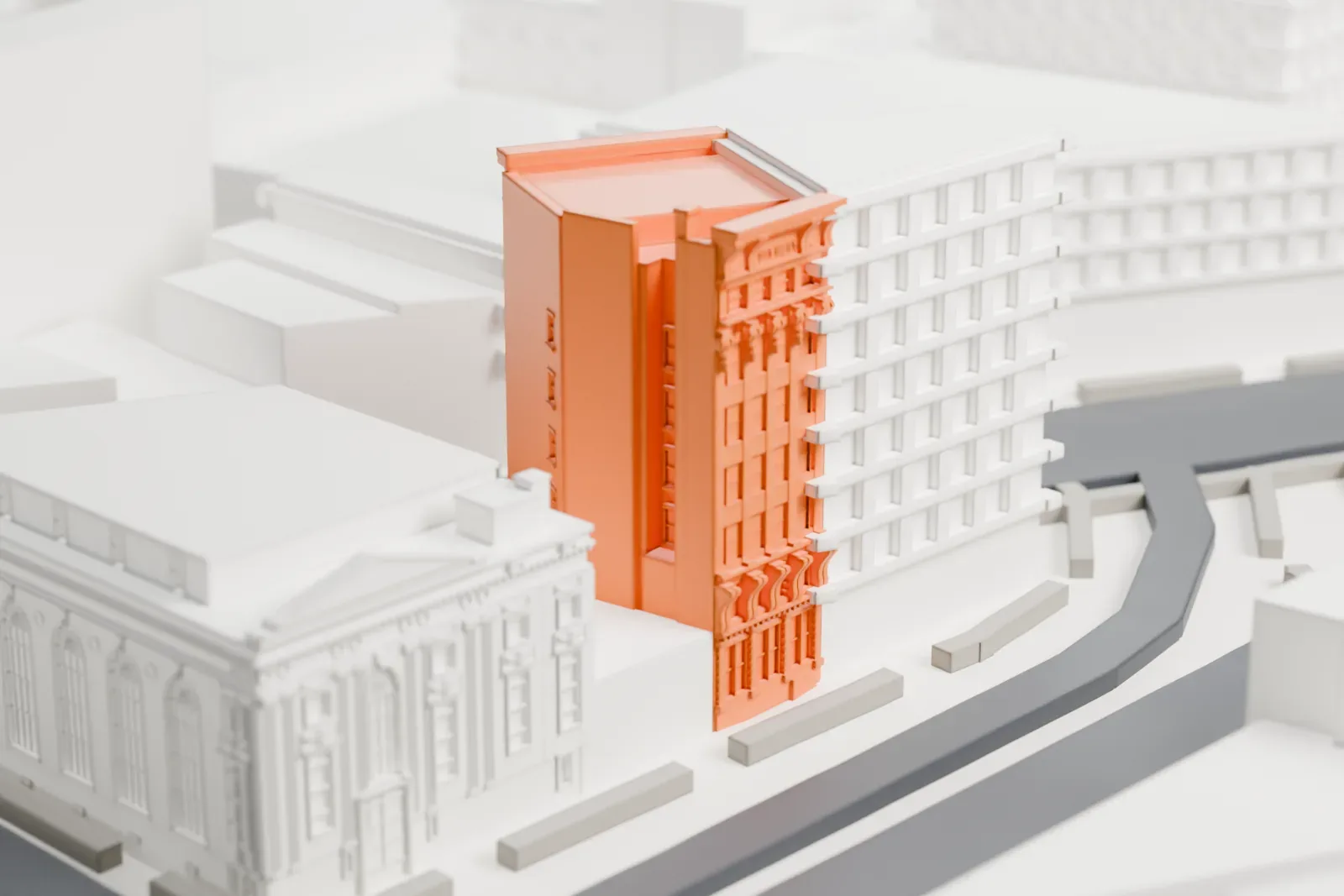 A white 3D print of the Haffen Building, a tall, narrow office building with a richly ornamented front, beside larger plain buildings and a curving street.