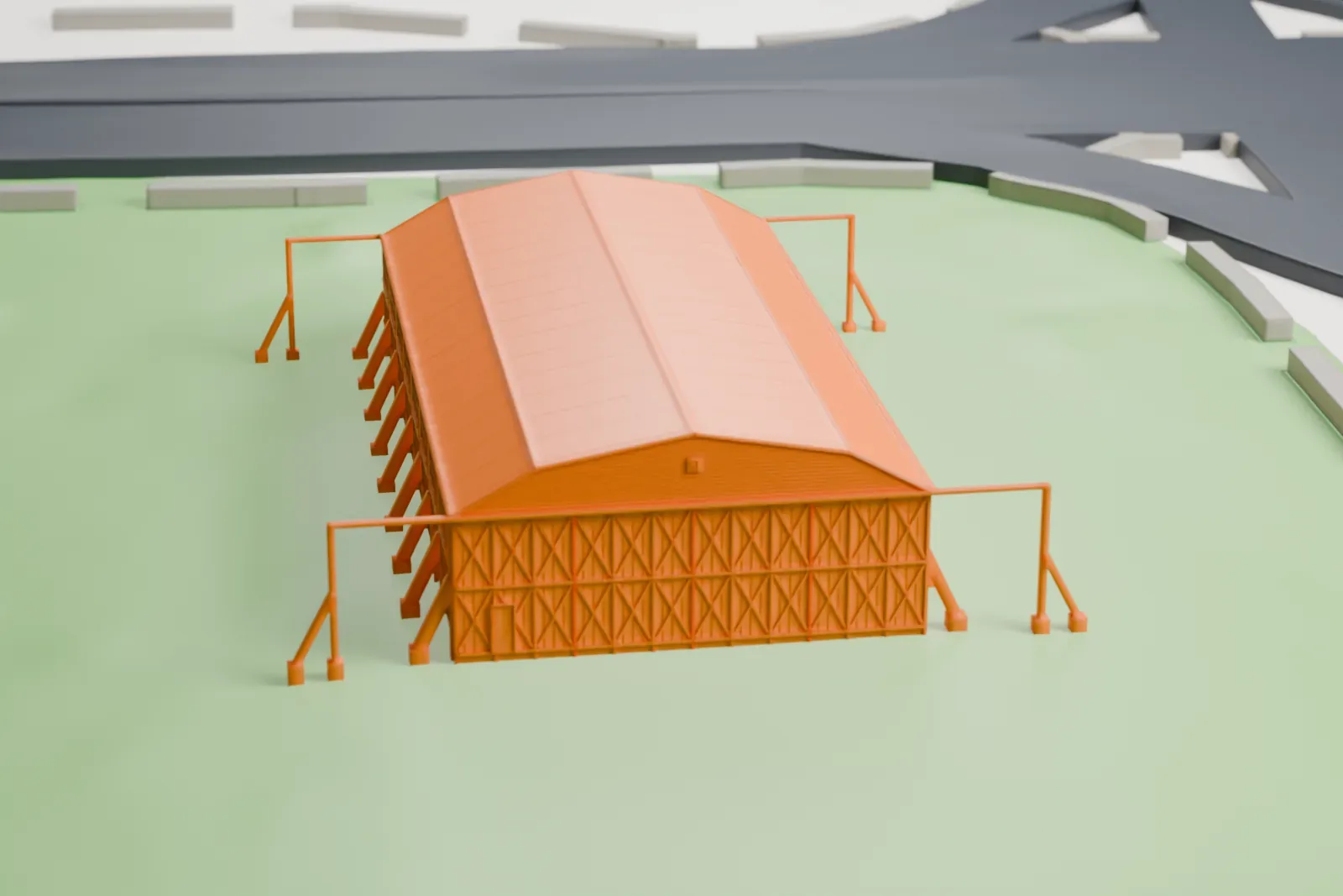 A white 3D print of Hangar 9, a long hangar with a broad curved roof, rows of windows along its sides and crossed bracing on its ends, on open grass beside roads.