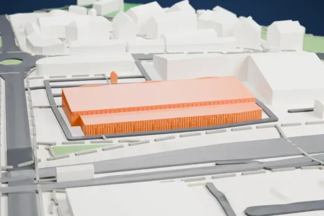 A white 3D print of the Hangaren Lade historic aircraft hangar model in Trondheim, with the streets around it.