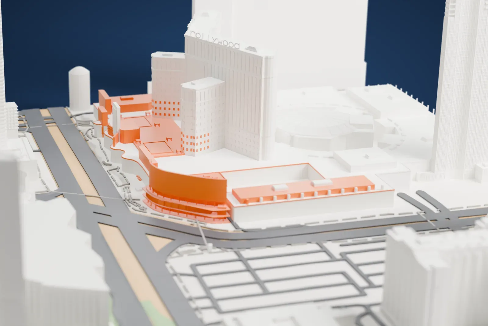 A white 3D print of Harmon Corner, a curved three-story building topped by a tall curved screen wall braced from behind, on a street corner between larger buildings and wide roads.