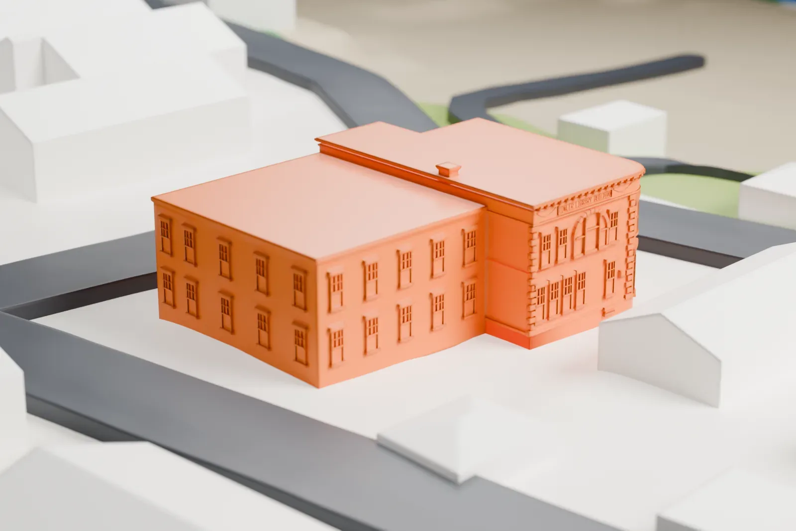 A white 3D print of the Haverstraw King's Daughters Public Library, a flat-roofed brick building with a rounded corner and a side wing, on a block between streets and small buildings.