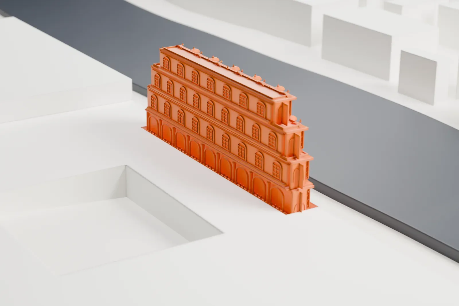 A white 3D print of Hawa Mahal, a narrow stepped facade covered in small windows and domed canopies, standing beside a wide street among large flat-roofed buildings.