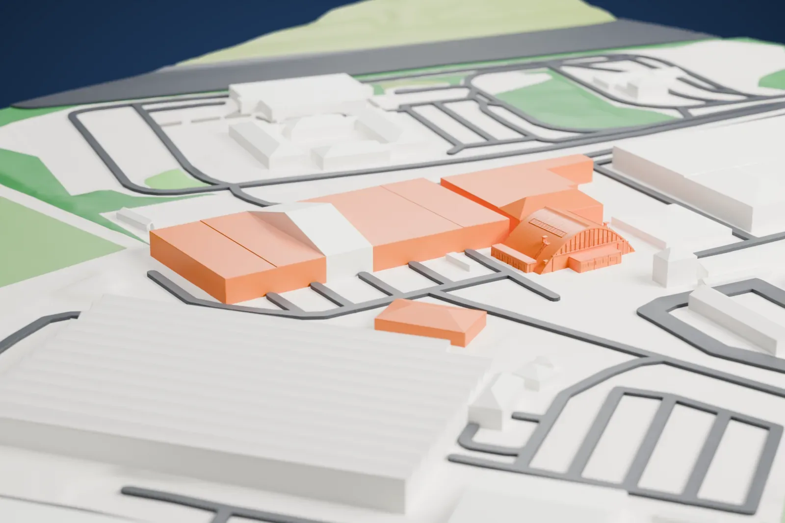 A white 3D print of the arched hangar at Heston Aerodrome, with its curved barrel roof, skylight strips and a small side building, among larger blocks and roads.
