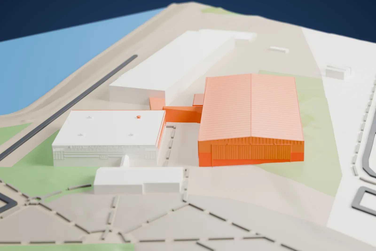 A white 3D print of the two Hill Aerospace Museum display hangars, joined by a short link, beside a pond, roads and other large buildings.