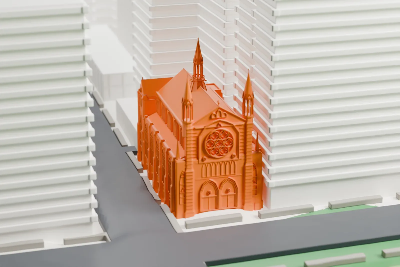 A white 3D print of Holy Trinity Lutheran Church, a stone front with pointed pinnacles and a rose window, beside a street and strip of park with tall buildings behind.