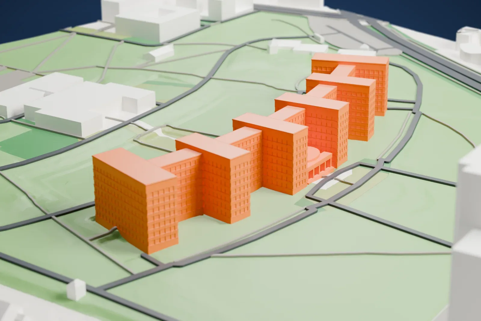 A white 3D print of the IG Farben Building, a long curved office block with a central portico, among the surrounding streets and buildings of Frankfurt.