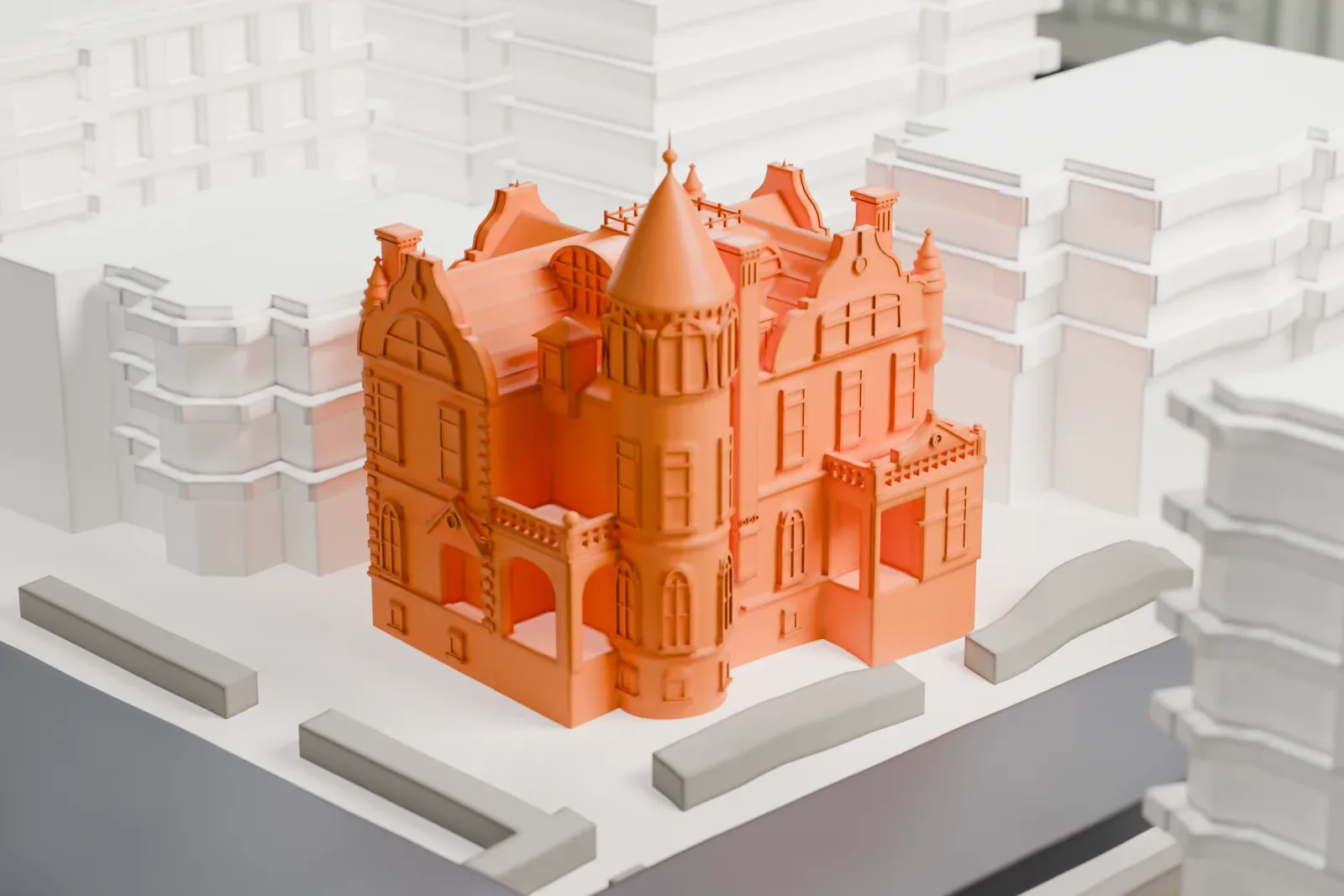A white 3D print of the James Bailey House, a mansion with a round corner tower under a cone roof, ornate gables and a balcony, set between streets and larger buildings.