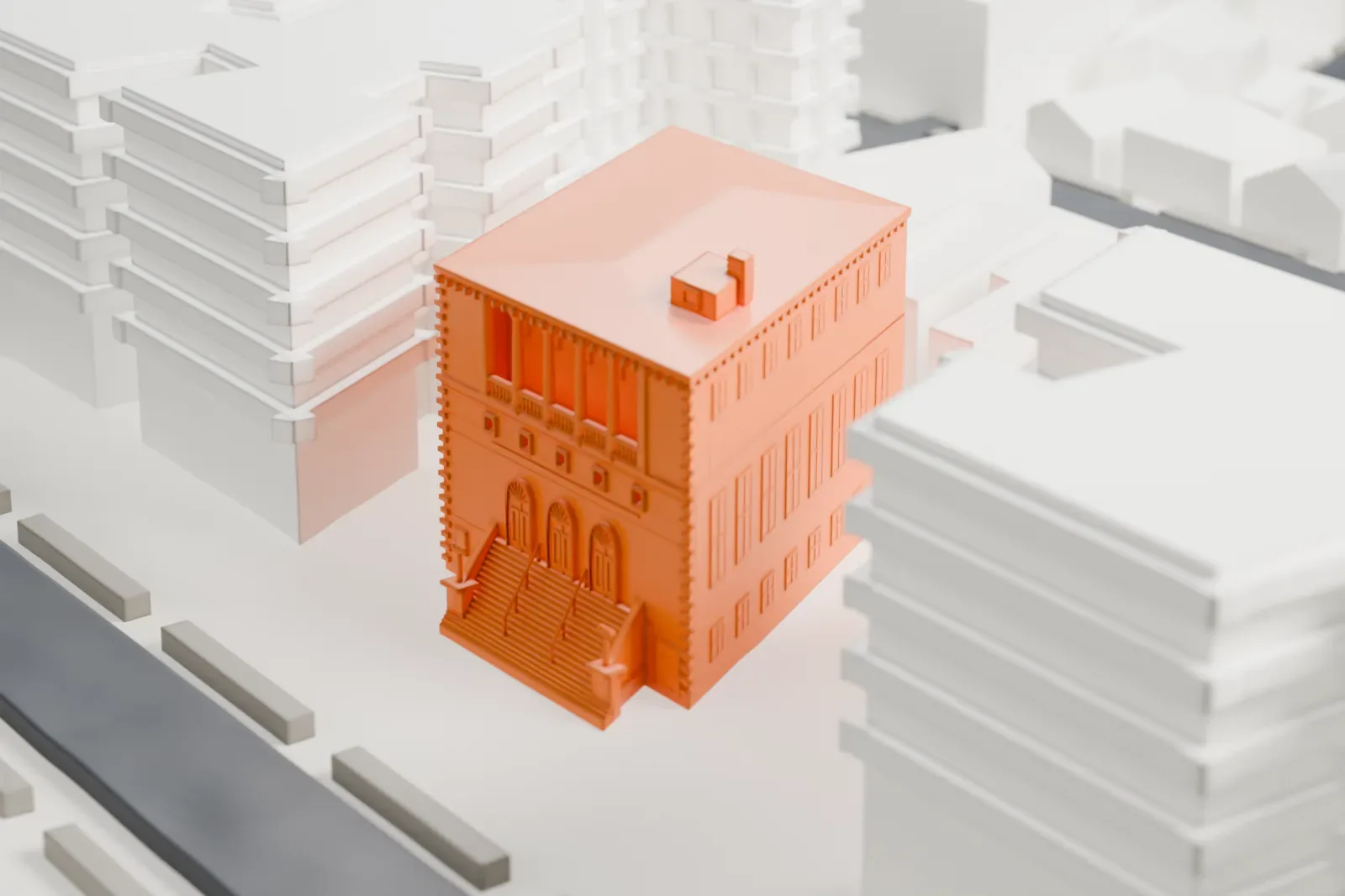 A white 3D print of the Jewish Center of Brighton Beach, a four-story building with a hipped roof and a small box on top, surrounded by larger buildings and streets.