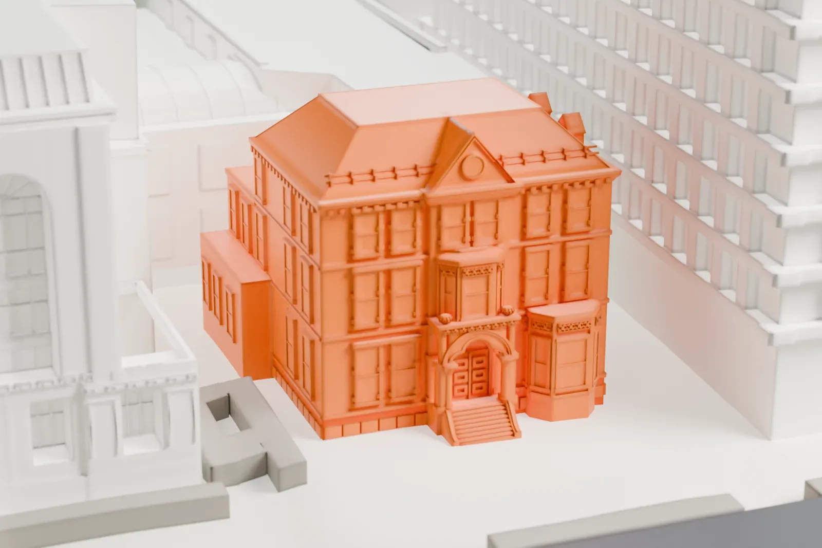 A white 3D print of the John Ballantine House, a three-story house with a hip roof, a gabled center bay and a front entrance with steps, set between much larger buildings.