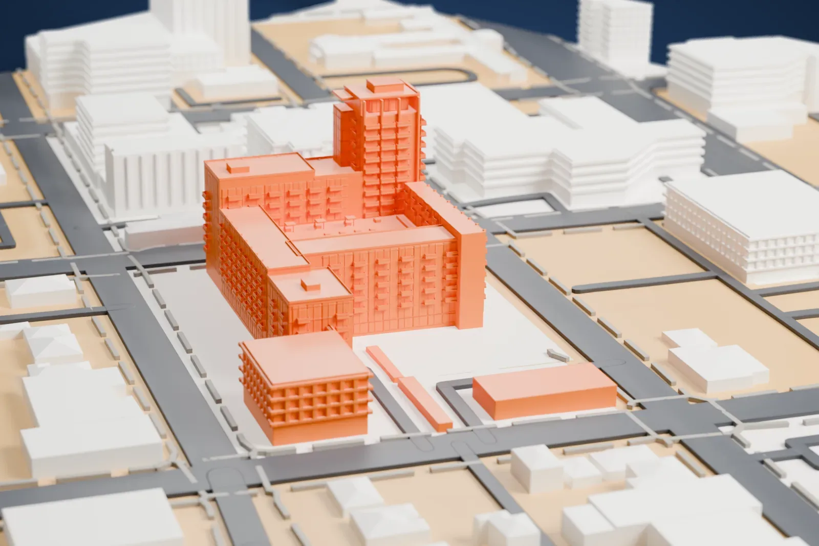 A white 3D print of Juhl, a block of residential buildings with one taller corner tower around a courtyard, among streets and low buildings.