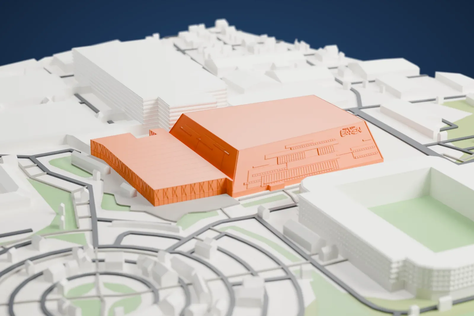 A white 3D print of Jyske Bank Boxen, a large box-shaped arena with sloping walls and a lower hall beside it, surrounded by roads and other buildings.