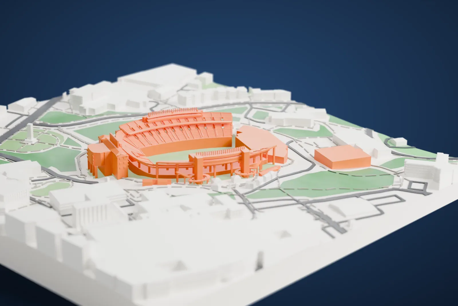 A white 3D print of Kenan Stadium, a horseshoe-shaped stadium with tiered stands and a tall block at one corner, surrounded by buildings and green patches.