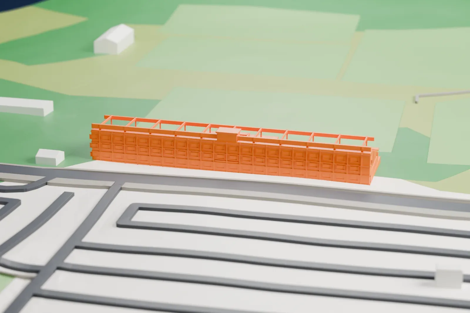 A white 3D print of King Peter I Stadium, a long grandstand with an open roof frame and rows of seats, on grassy ground beside roads.