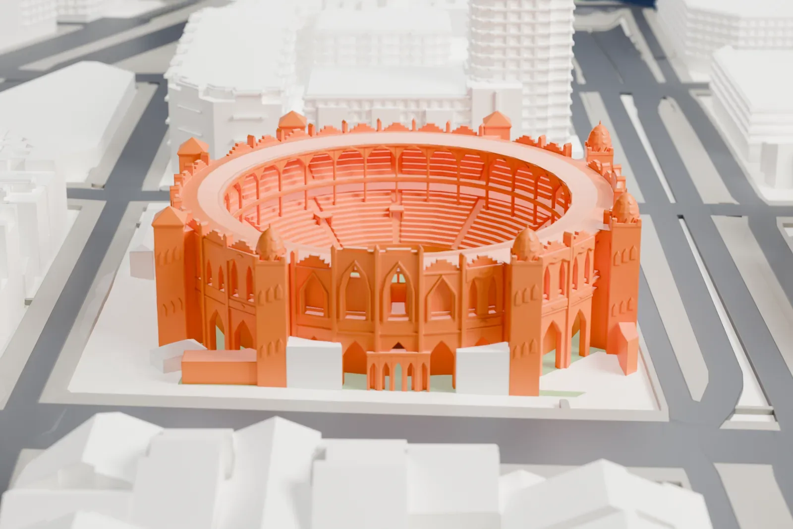 A white 3D print of La Monumental, a circular brick bullring with domed corner towers, among the surrounding streets and buildings of Barcelona.